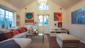 Un salón amplio con techo alto, un ventanal grande y una zona de estar acogedora.