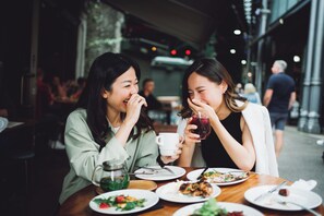 Two people dining at an outdoor table with various dishes and drinks. - Crowne Plaza Nashville Airport by IHG (Nashville)