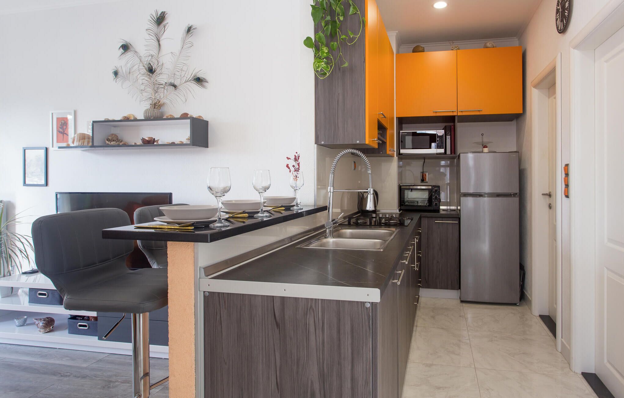 A modern kitchen with grey cabinetry, a stainless steel sink, and a built-in oven.