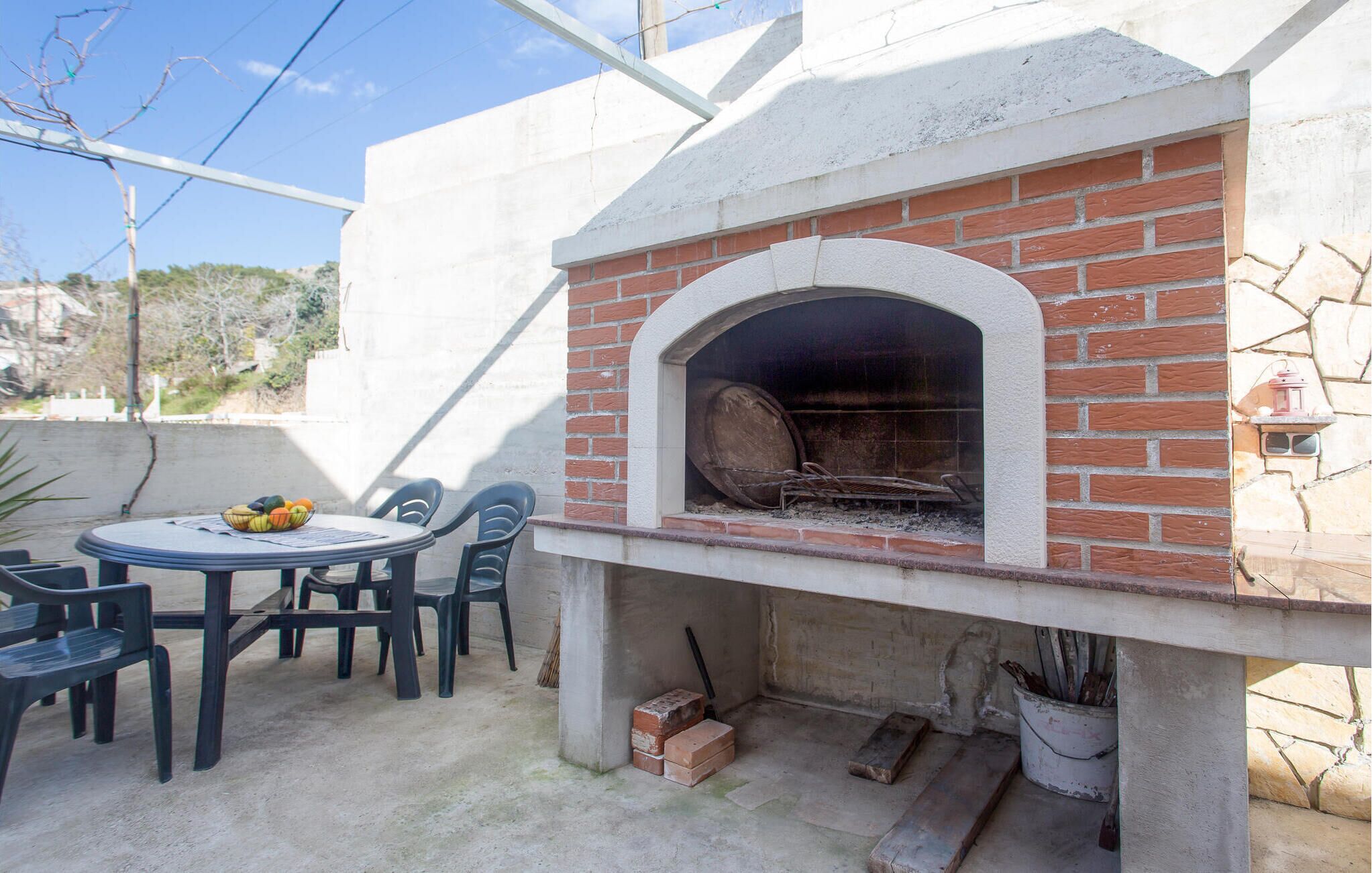 An outdoor brick oven with a table and chairs nearby.
