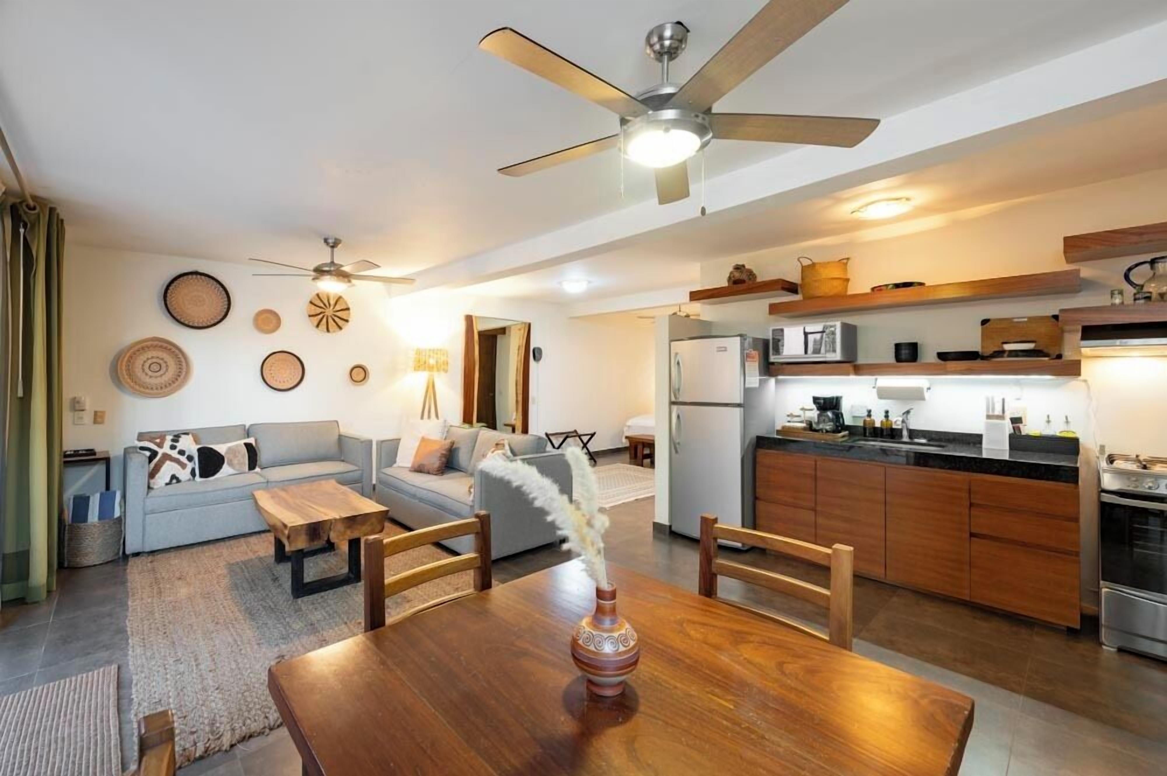 A compact living space with a dining area, kitchen, and a ceiling fan.