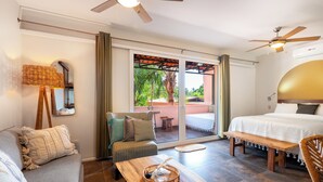 Une chambre d’hôtel avec un lit, un canapé, une table basse en bois, un ventilateur de plafond et une vue sur l’extérieur.