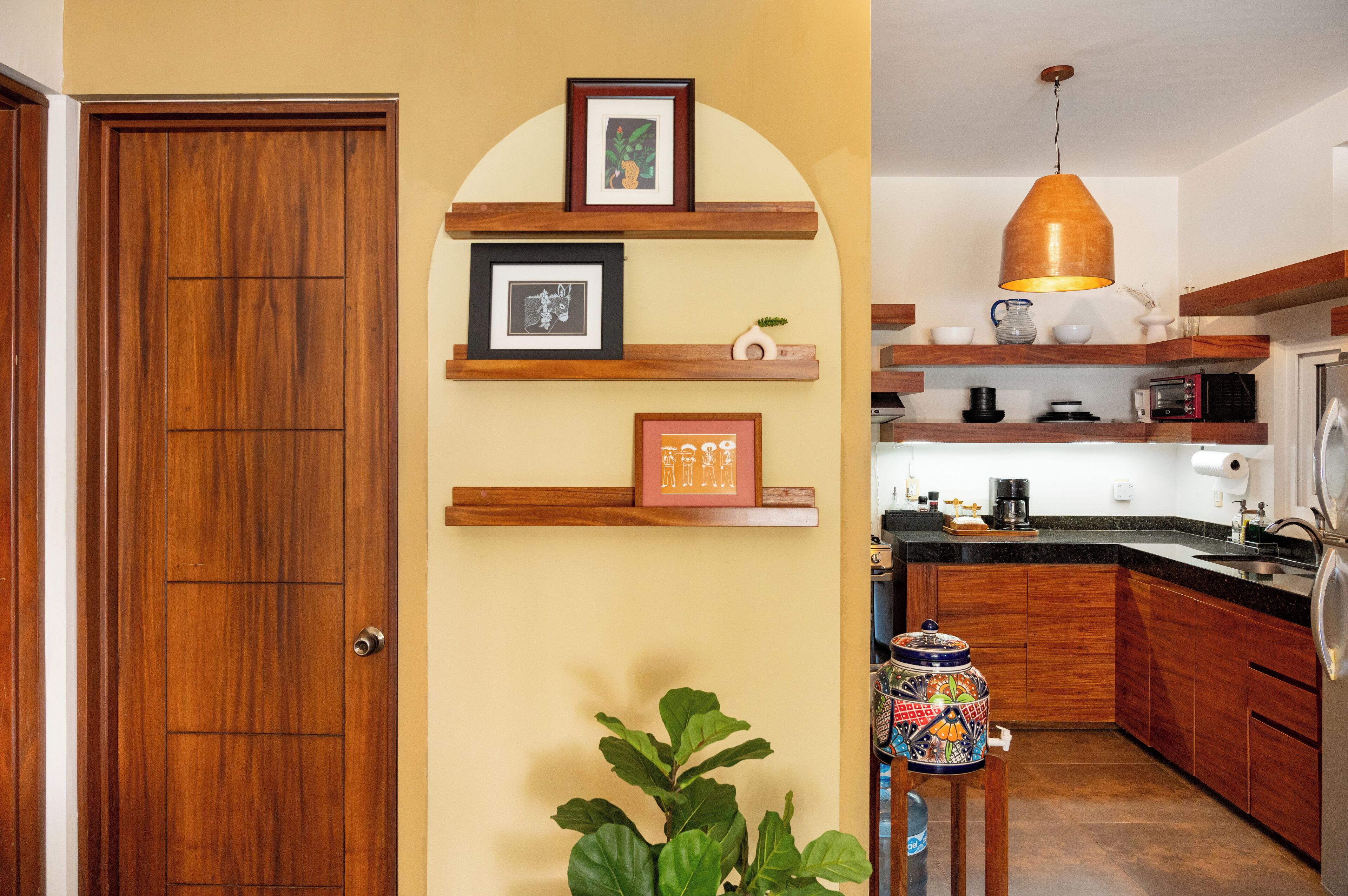A kitchen with wooden cabinets, a built-in microwave, and a hanging pendant light.