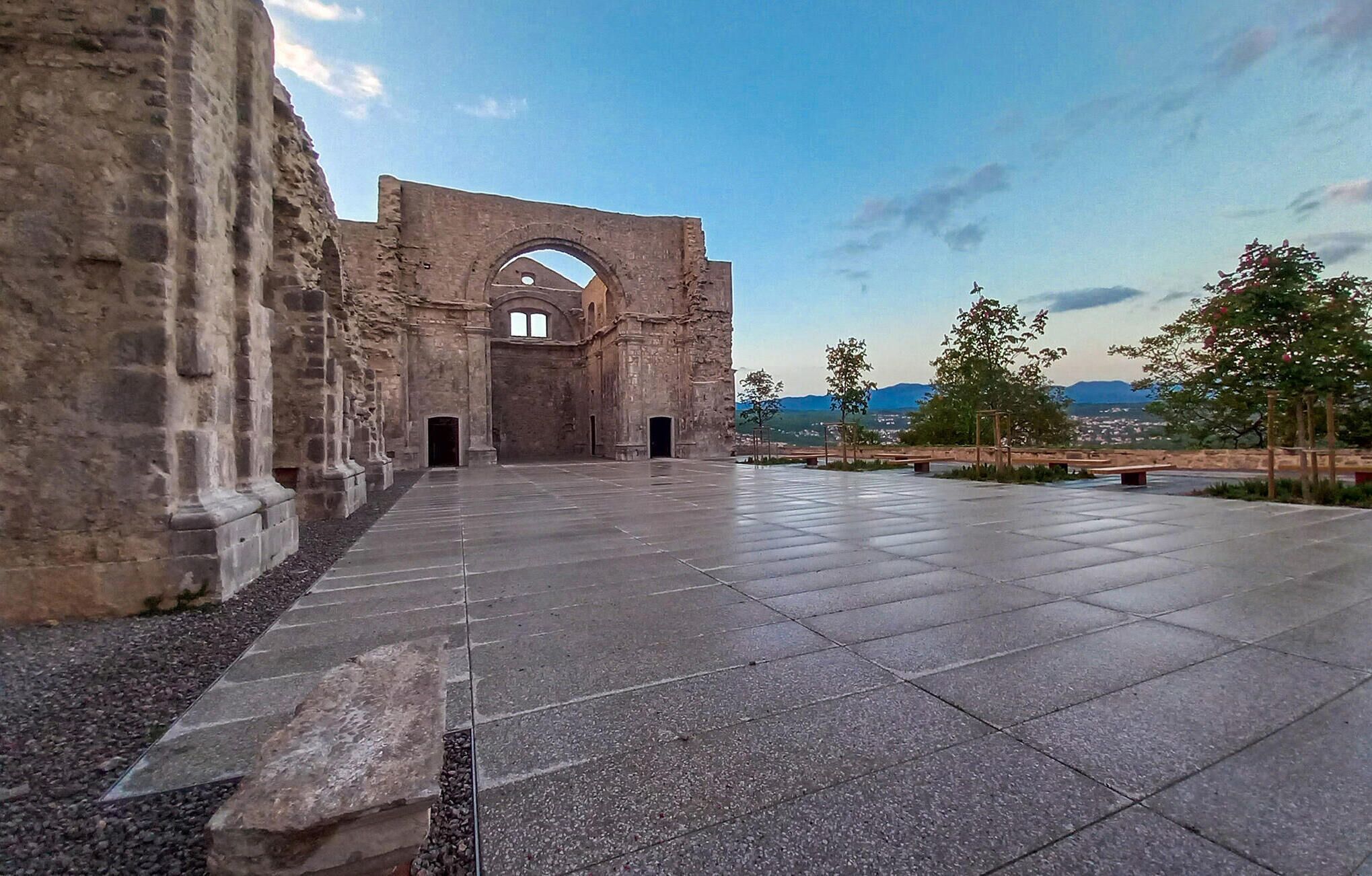 An ancient stone structure with a large archway and a paved courtyard.