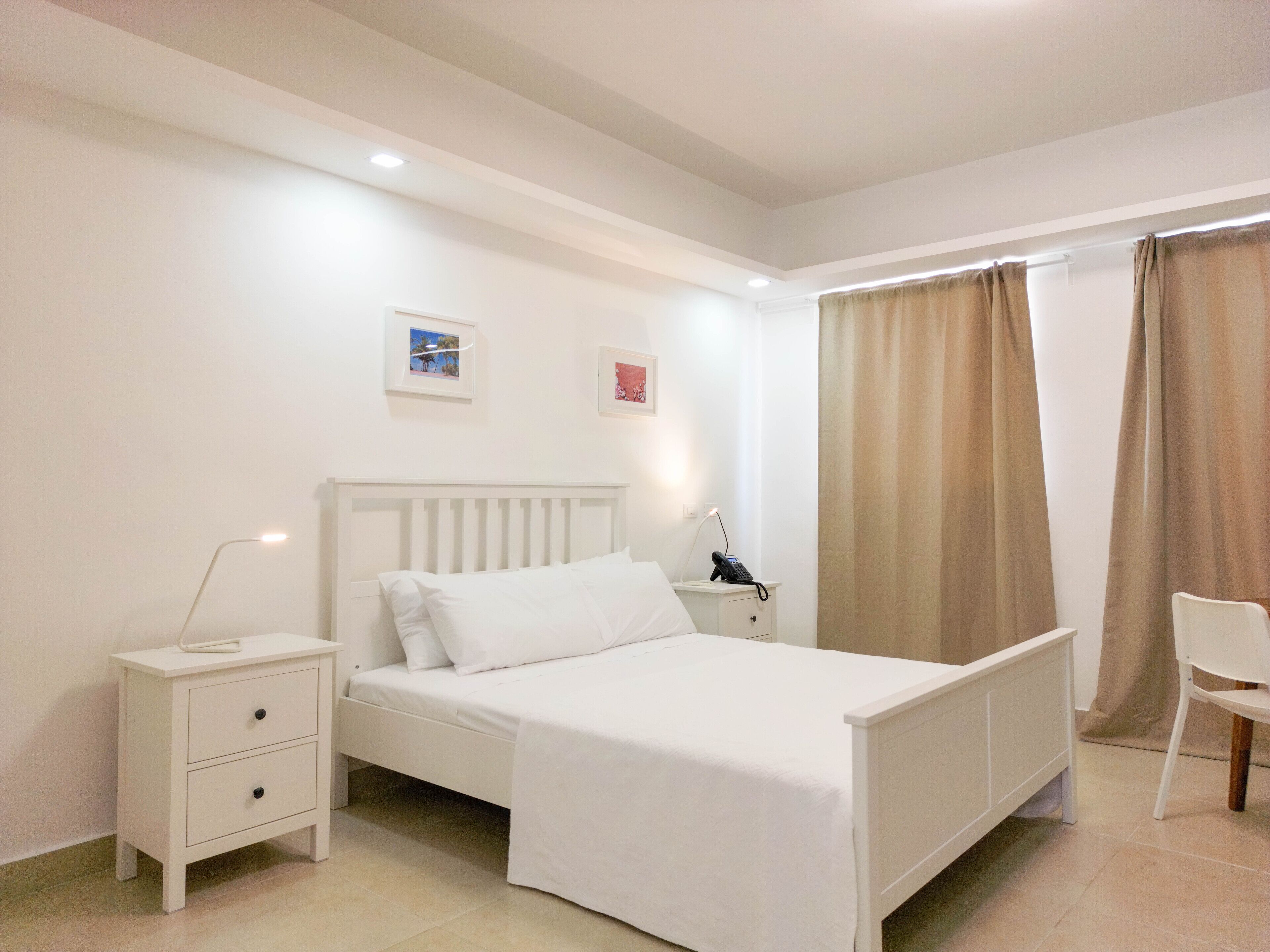 Un dormitorio ordenado con una cama individual, mesitas de noche, una silla y un escritorio pequeño.