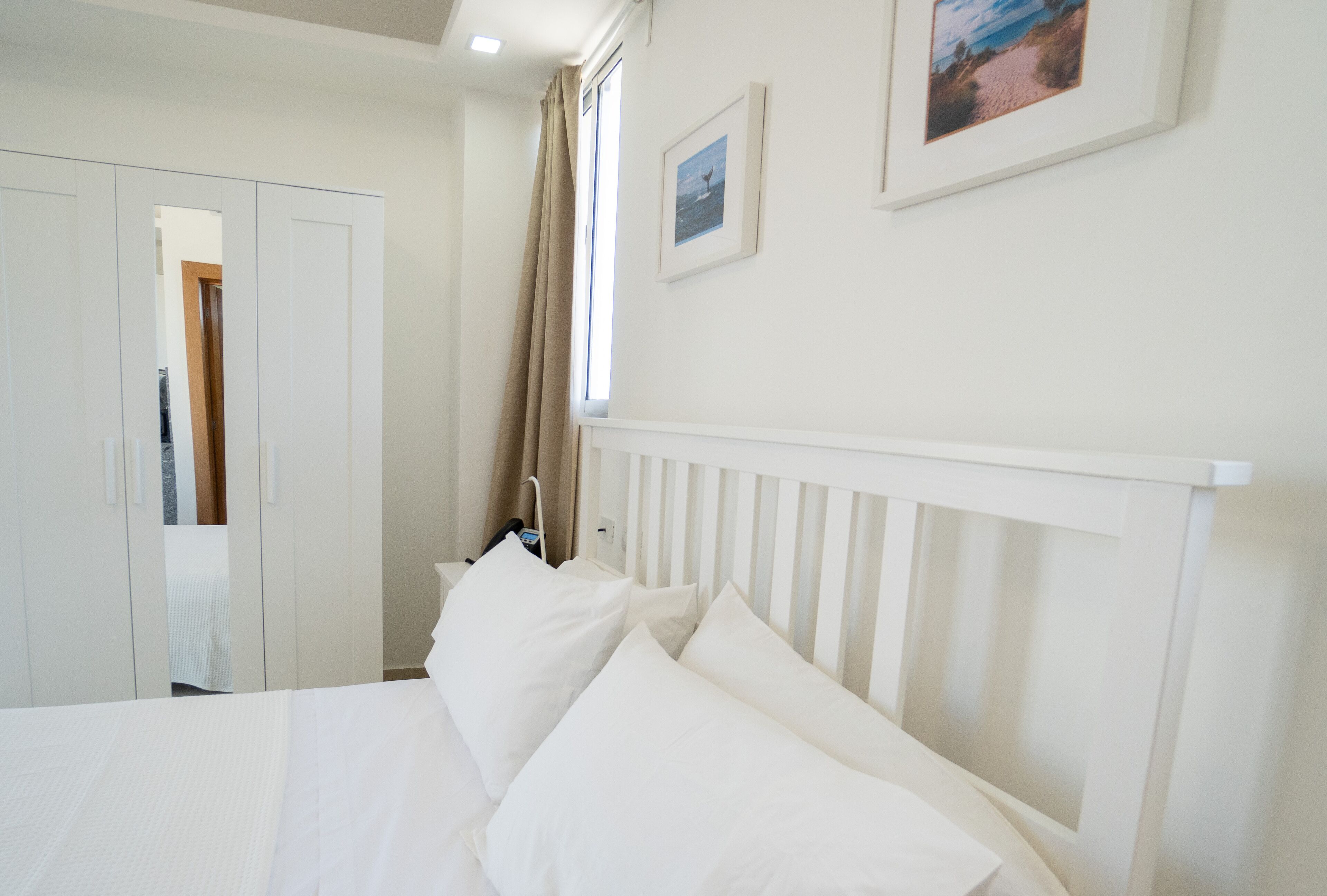 A hotel room with a bed, a wardrobe, and a window with curtains.