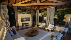 Un espacio exterior con una chimenea, sofás y sillones dispuestos alrededor de una mesa de centro.