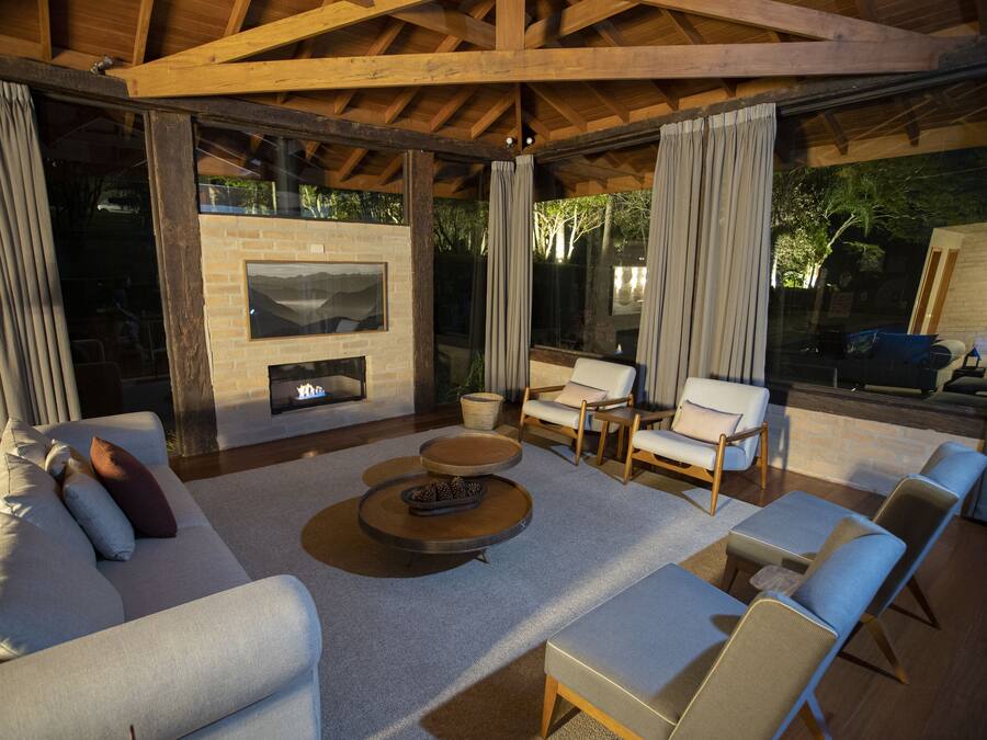 An outdoor living area with a fireplace, sofas, and chairs arranged around a central coffee table.