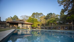 Una piscina con agua cristalina que refleja árboles y un edificio con tejado de baldosas.