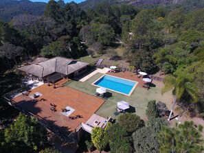 Una gran piscina rodeada por un deck de madera con asientos exteriores y sombrillas.