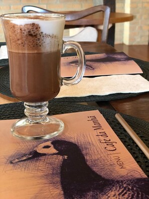 Una taza de café con espuma, sobre un posavasos con un menú que muestra el retrato de una mujer.