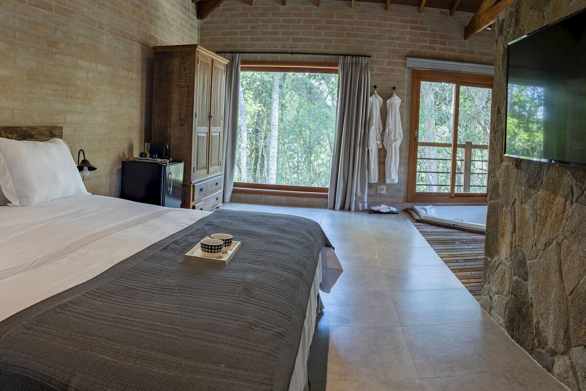 Un dormitorio con una cama grande, cabecera de madera y pared de piedra.