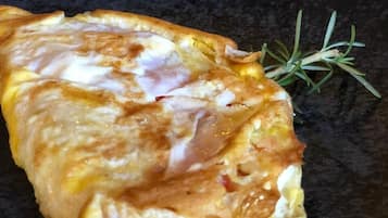 En sammenfoldet omelet på en sort tallerken med en rosmarin kvist.
