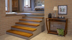 Una escalera con escalones de madera que lleva a un dormitorio con pared de piedra y un cuadro enmarcado.