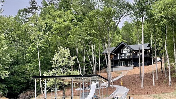 Un chalet au bord du lac, doté d’un quai, d’un espace salon couvert et d’un toboggan.