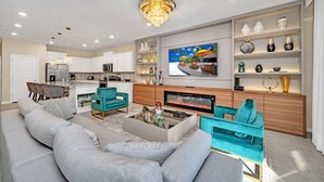 Een moderne woonkamer met een open haard, een eethoek en een keuken op de achtergrond.