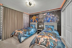Una camera da letto con due letti, un murale al muro e una ventola a soffitto.