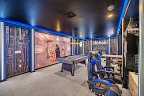 Una stanza con tavolo da biliardo, poltrone da gioco e oggetti da collezione di Star Wars.