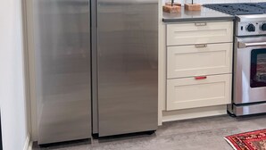 A kitchen with a stainless steel double refrigerator, a gas stove, and wooden decorative items on the countertop.
