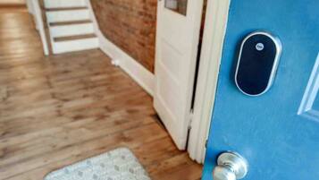 Una puerta azul con cerradura Yale, suelo de madera y alfombra blanca con diseño.