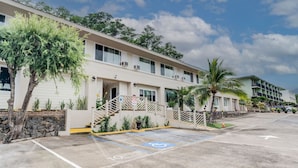 A hotel with a parking lot, a covered walkway, and a building with multiple floors and balconies.