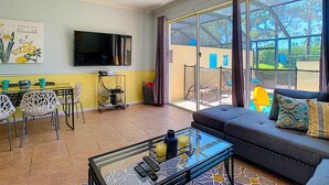 Un salon comprenant un canapé, une table basse, un téléviseur et un coin repas avec des chaises et une table.