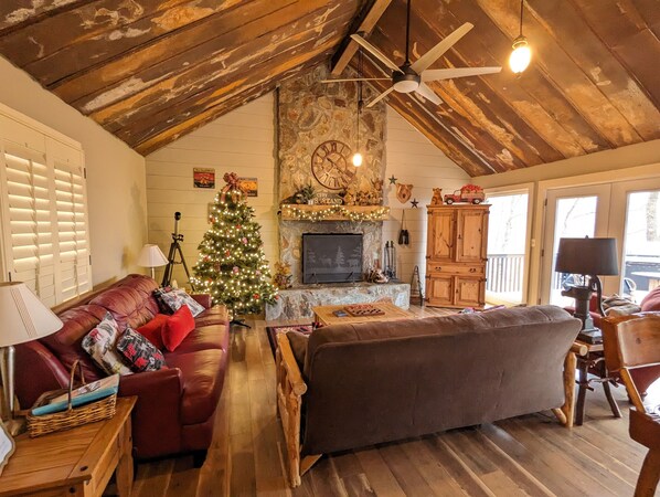 A cozy living room with a fireplace, a Christmas tree, and wooden furniture.