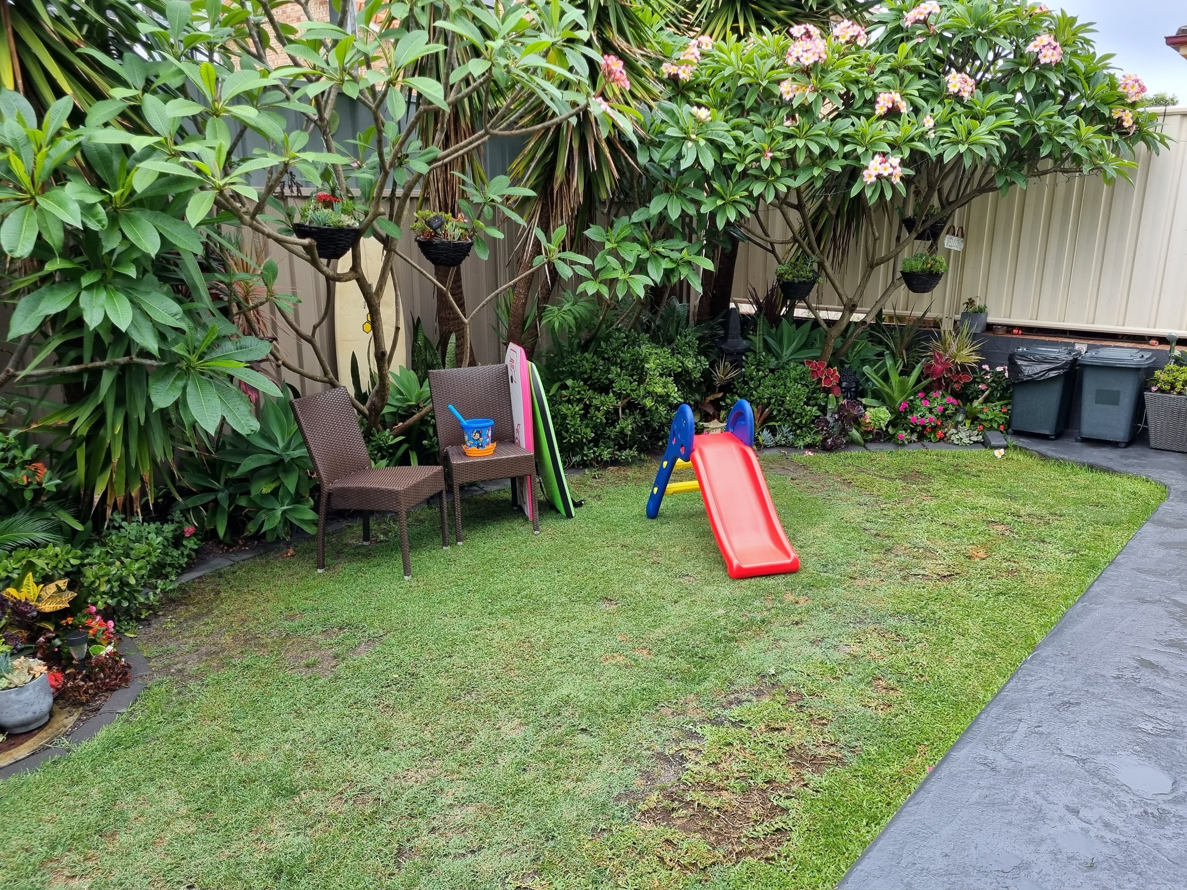 A backyard with a small play area, including a slide and a bench.
