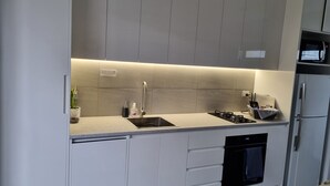 A modern kitchen with a built-in stove, sink, and oven, along with a microwave and refrigerator.