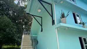 A two-story building with a light blue exterior, a staircase leading to the entrance, and potted plants on the ground level. - this place will bring lots of peace to enjoy the sun and the beach! (San Antero)