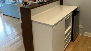 Eine moderne Küche mit Kochinsel, Essbereich mit Sofa und großem Fenster mit Vorhängen.
