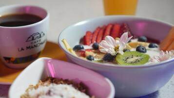 A breakfast setting with a glass of orange juice, a bowl of cereal with fruits, and a cup of coffee.