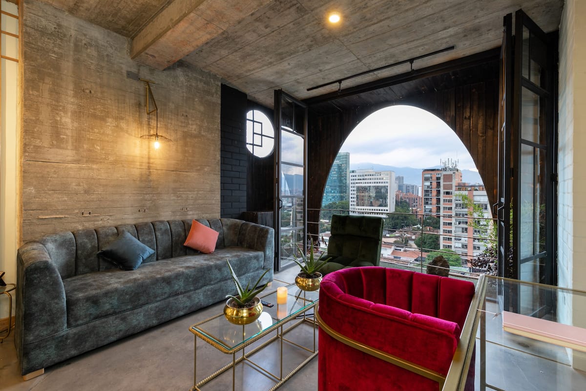 A modern living room with a grey sofa, a red chair, and a glass coffee table.