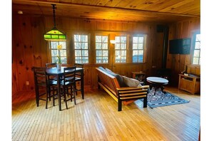 Living room has a futon sofa, gas fireplace, and a bistro table for 4
