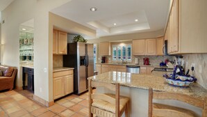 Una cocina amplia con armarios de madera, una isla central y un comedor con un sofá de cuero marrón.