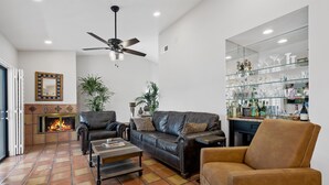 Una sala de estar con chimenea, sofás de cuero, una mesa de centro y una vitrina de vidrio con botellas.