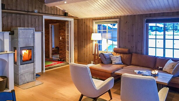 Ein gemütliches Wohnzimmer mit Kamin aus Stein, Holzwänden, einer Couch und einem Couchtisch.