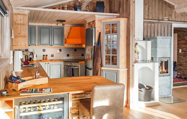 A modern kitchen with wooden cabinets, a central island, and a built-in fireplace.