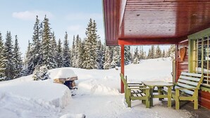Eine Holzhütte mit überdachter Veranda, einer Bank und einem Tisch.
