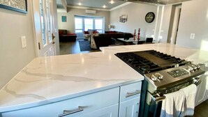 A modern kitchen with a large island, stainless steel appliances, and a view into the living area. - Luxurious Penthouse with Bay View in Old Town Tacoma (Tacoma)
