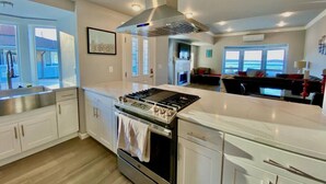 A modern kitchen with stainless steel appliances, white cabinetry, and a large island. - Luxurious Penthouse with Bay View in Old Town Tacoma (Tacoma)