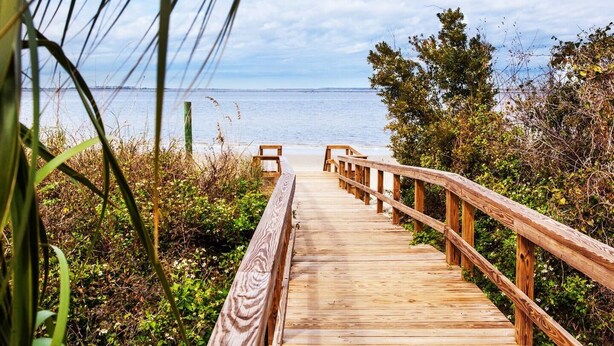 Una pasarela de madera que conduce a una playa, con una vista despejada del océano.