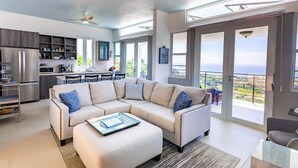 Een moderne woonkamer met een hoekbank, een eethoek en een keuken. Er is een balkon met uitzicht.
