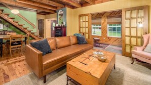 A cozy living room with a wooden ceiling, a brown leather sofa, a wooden coffee table, and a staircase leading to another room. - 3 BR/3.5 BA w/ Hot Tub & 12 min drive to Ash Cave (New Plymouth)