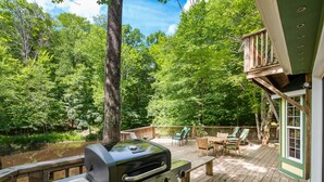 A barbecue grill on a wooden deck with a view of a forest and a lake. - 3 BR/3.5 BA w/ Hot Tub & 12 min drive to Ash Cave (New Plymouth)