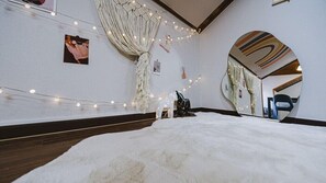 A room with a large mirror, string lights, a white fur rug, and a hammock. - Pension Irum (Gapyeong)
