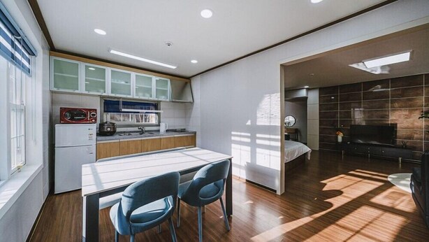 A modern kitchen with a dining area, a TV in the living room, and a large window providing natural light. - Pension Irum (Gapyeong)
