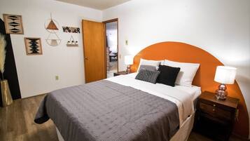A bedroom with a bed, a nightstand, a lamp, and wall decorations.