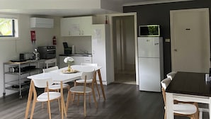 Una cocina moderna con armarios blancos, una zona de comedor con mesa y sillas blancas, y una mesa de comedor de madera oscura.