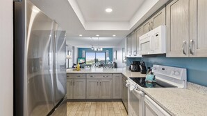 Una cocina moderna con electrodomésticos de acero inoxidable, armarios de madera y encimera de granito.